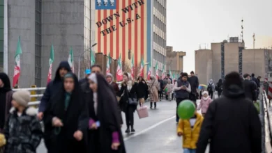 إيرانيون خلال فعالية دينية يمرون أمام لوحة جدارية مناهضة للولايات المتحدة في وسط طهران. 4 فبراير 2026