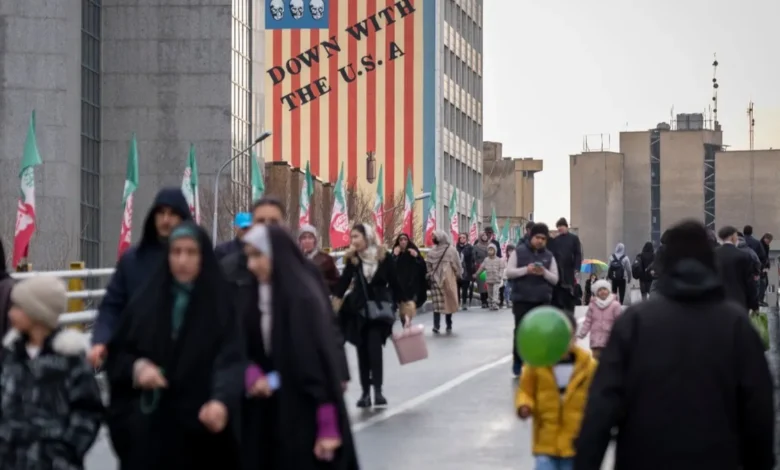 إيرانيون خلال فعالية دينية يمرون أمام لوحة جدارية مناهضة للولايات المتحدة في وسط طهران. 4 فبراير 2026