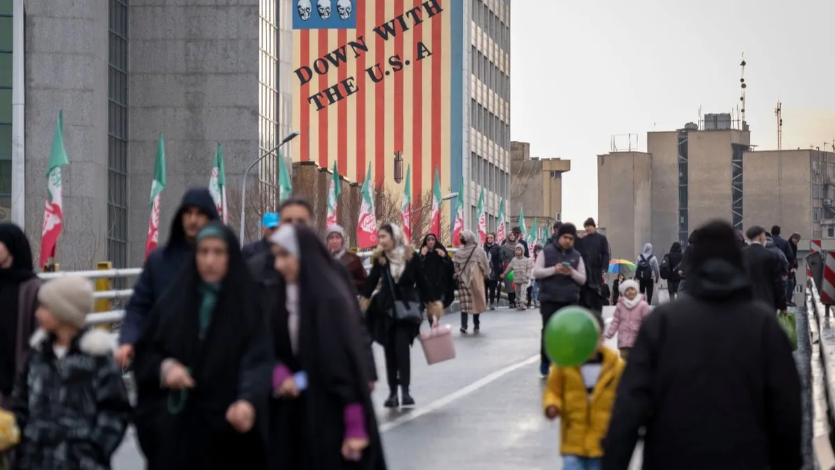 إيرانيون خلال فعالية دينية يمرون أمام لوحة جدارية مناهضة للولايات المتحدة في وسط طهران. 4 فبراير 2026